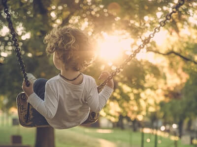 child swinging on a swing with back to us