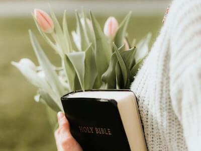 person holding bible and tulips