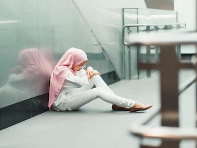 woman with pink head scarf sitting on floor of building
