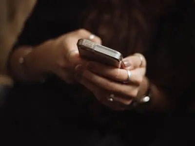 person holding a phone and using thumbs to click phone