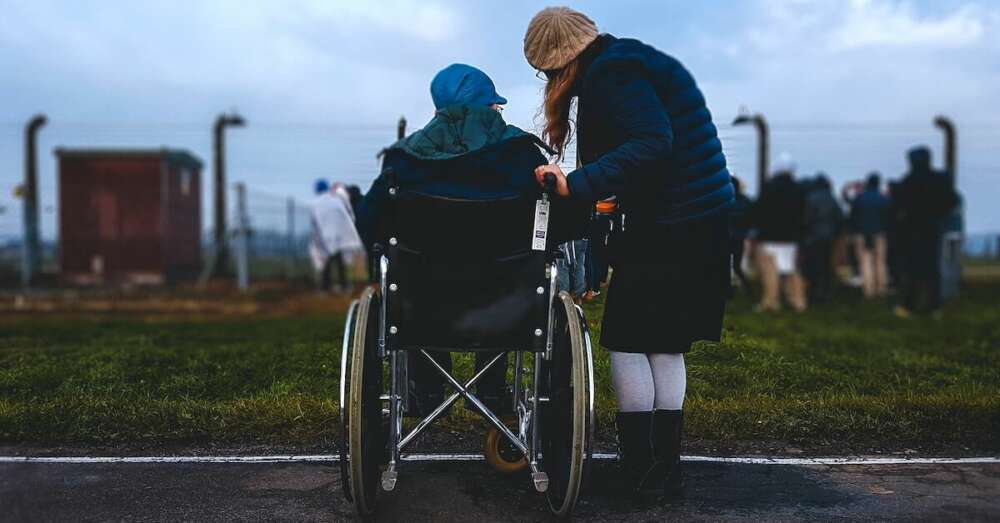 Elderly person in wheelchair is at a park with their carer