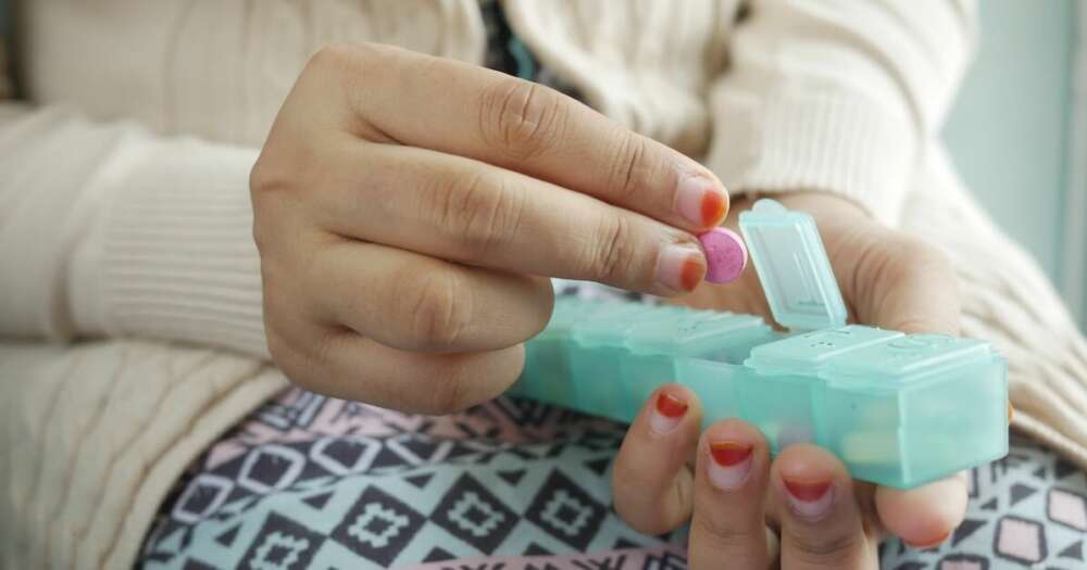 woman holding a pill box with pills in her fingers